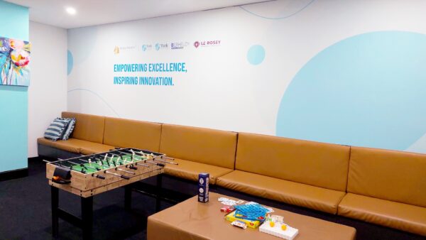 The student lounge common space on Level 4 of the York Business Institute city campus. Photo shows the wall with the school logos, school slogan, seating for students, tabletop games, and a foosball table.